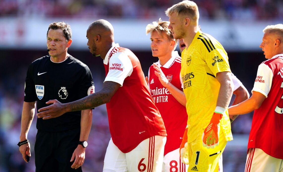 Arsenal players surround referee Darren England.