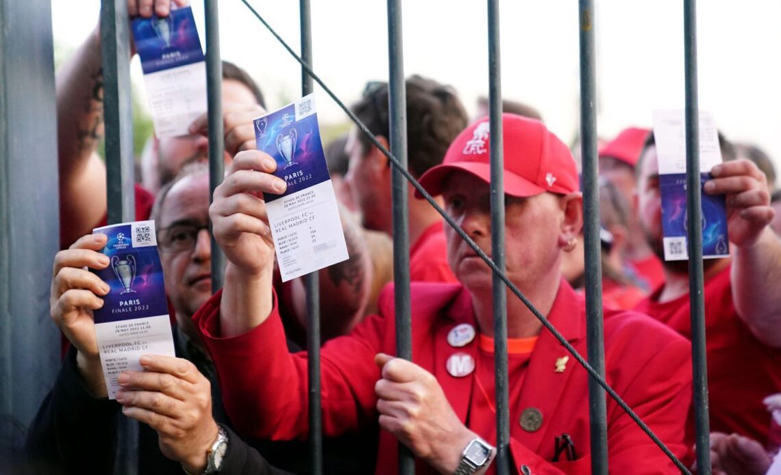 Liverpool fans show their tickets through bars