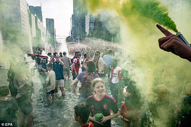 Feyenoord fans set off red, yellow and green flares and jumped into public fountains (above)