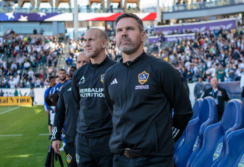 Galaxy coach Greg Vanney and his staff stand on the sideline and look ahead during the national anthem