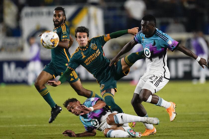 LA Galaxy midfielder Riqui Puig, center, shoots over Minnesota United midfielder Hassani Dotson.