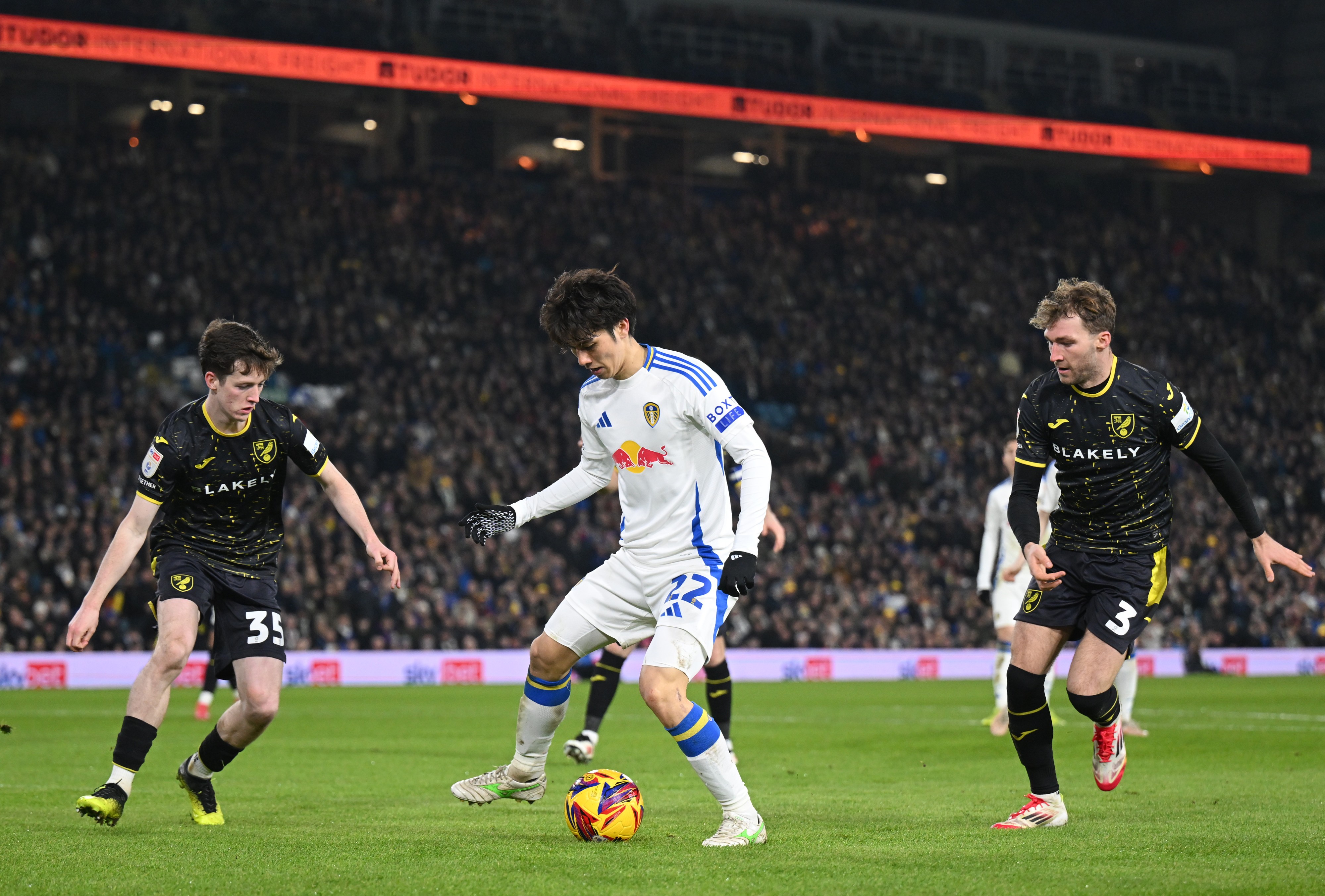 Ao Tanaka of Leeds United is challenged by Kellen Fisher and Jack Stacey of Norwich City